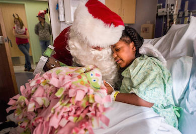 FRED ZWICKY/JOURNAL STAR Santa Bill Turney hugs Children's Hospital of Illinois patient Courtney Funchess of Peoria, 10, after bringing her a doll and a blanket for the holiday.